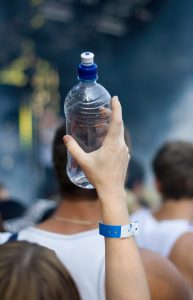 "Stock photo of water bottle at a rock concert or music festival, editorial style narrow depth of field."