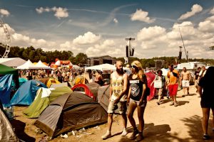 Kostrzyn Nad Odra, Poland - August 01, 2014: Young people walking through the campground, Woodstock festival stage in the background. 20th Woodstock Festival - the biggest open air ticket free rock music festival in Europe.